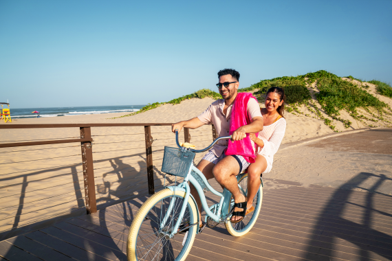 couple bicycling on boardwalk